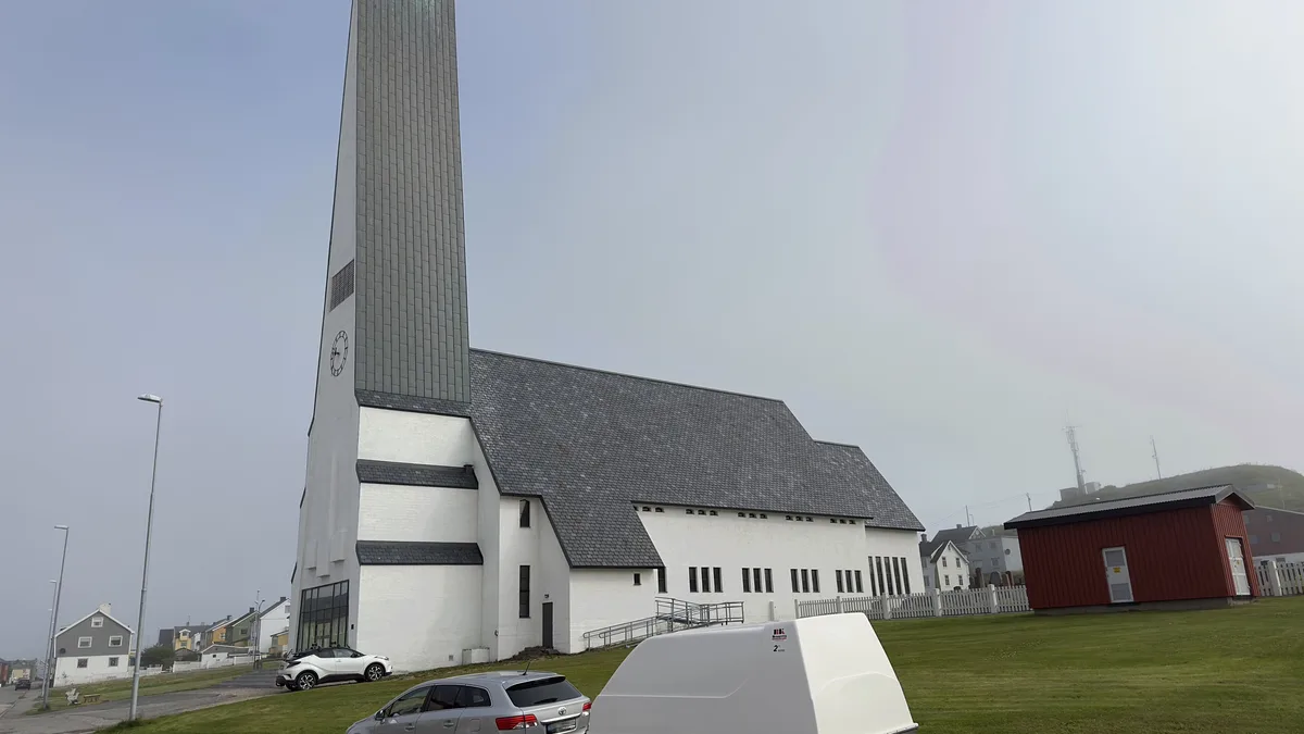 A small town street with a church and parked cars shrouded in fog in Vardø, Norway; illustrative stock photograph, not Afterlife with Archie artwork